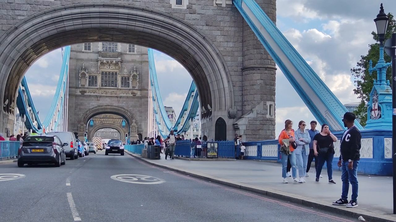 Looking through the arch of one of Tower Bridge's towers, with cars and people on the roadway