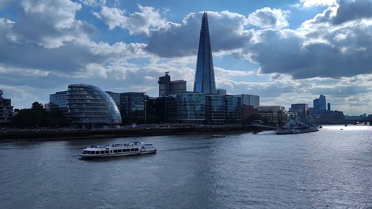 The Shard rising above riverside buildings, seen across the Thames with a boat on the water